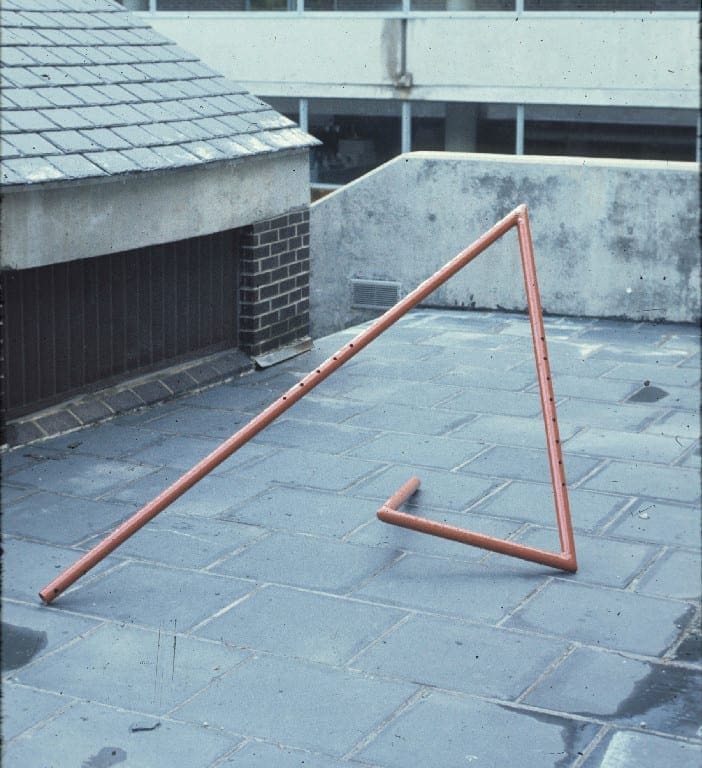 A triangle is laying on the ground in front of a garage.