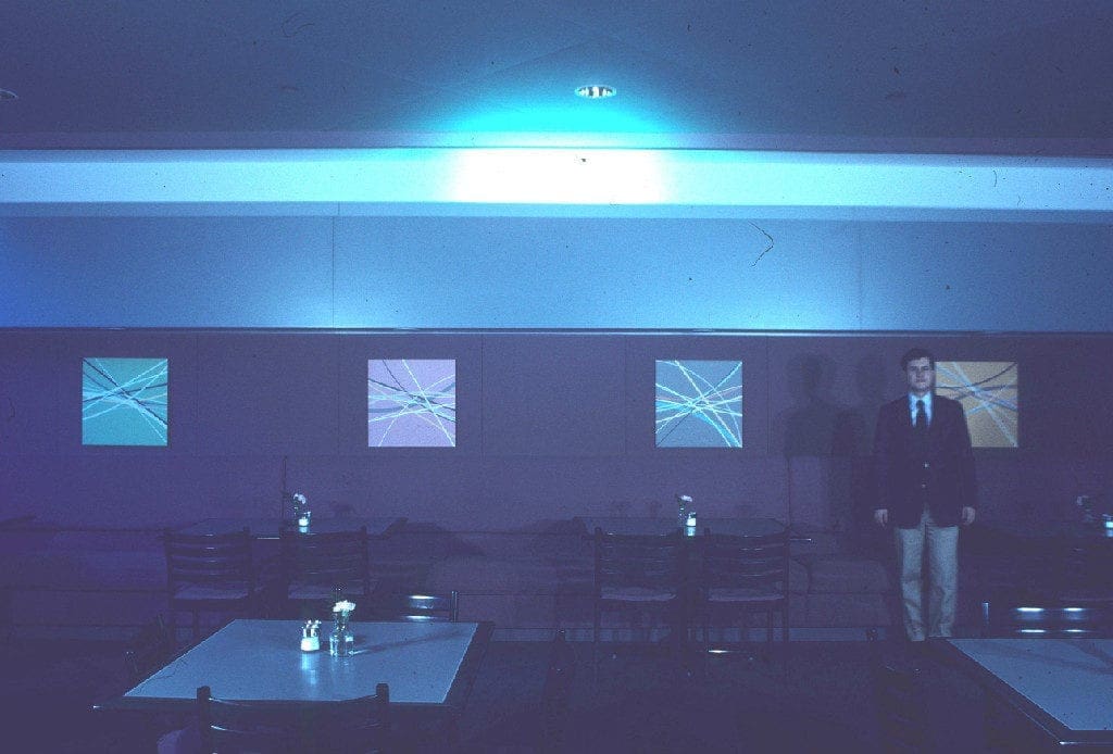 A man standing in front of two windows.