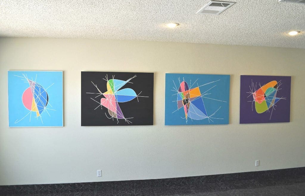 A wall with four paintings of different colors.