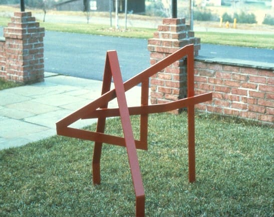 A red piece of wood sitting in the grass.