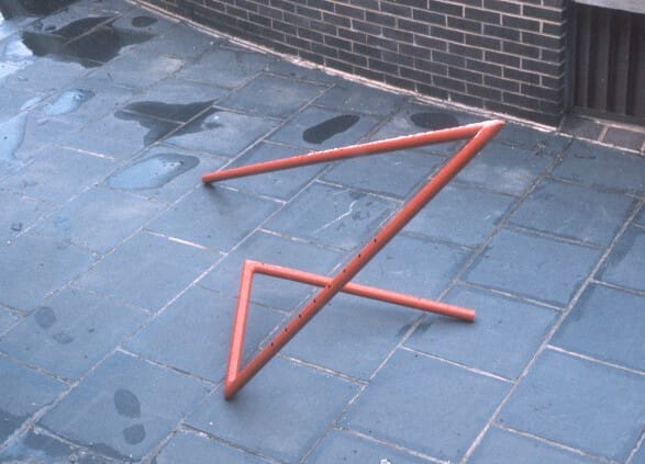 A red triangle is on the ground near a brick wall.