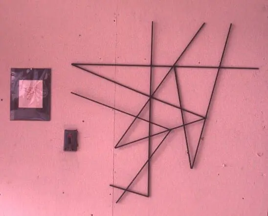 Abstract metal wall art on a pink background.
