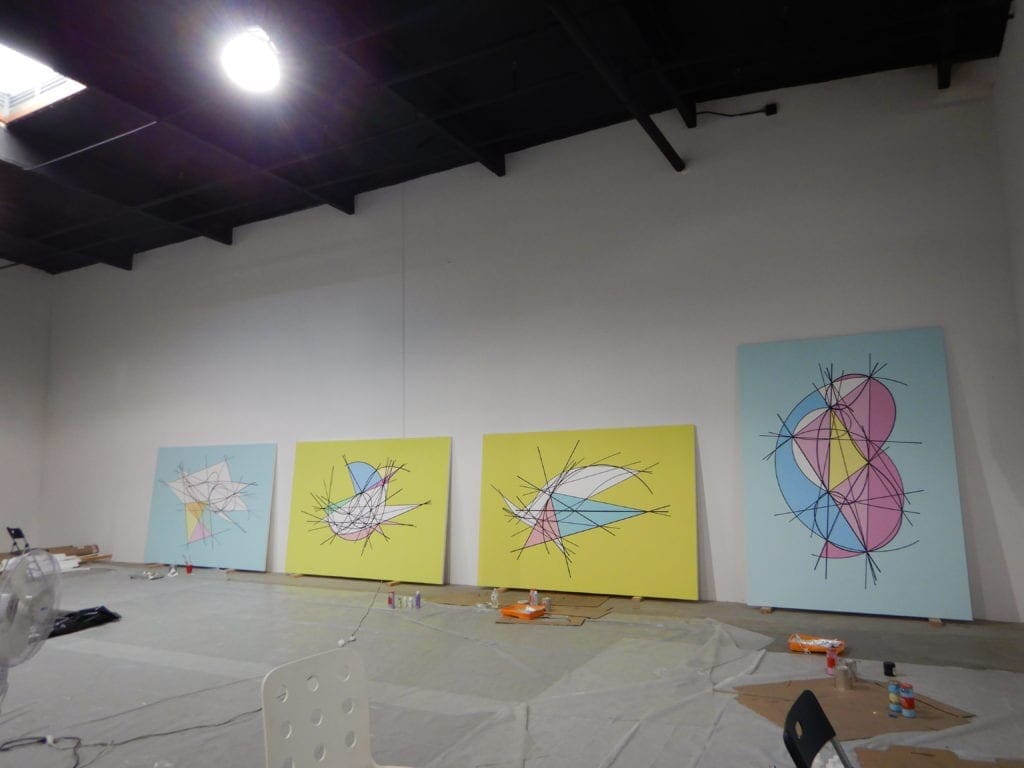 A group of paintings on the wall in a room.