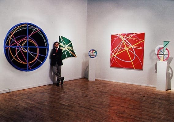 A woman holding an umbrella in front of two paintings.