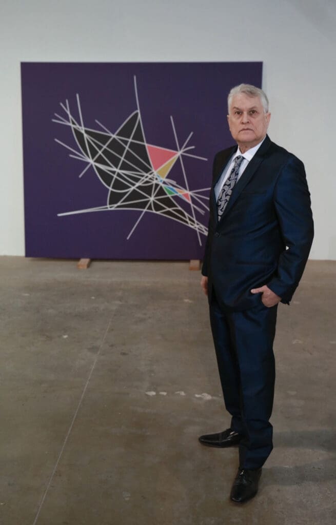 Grey-haired man in suit with abstract canvas