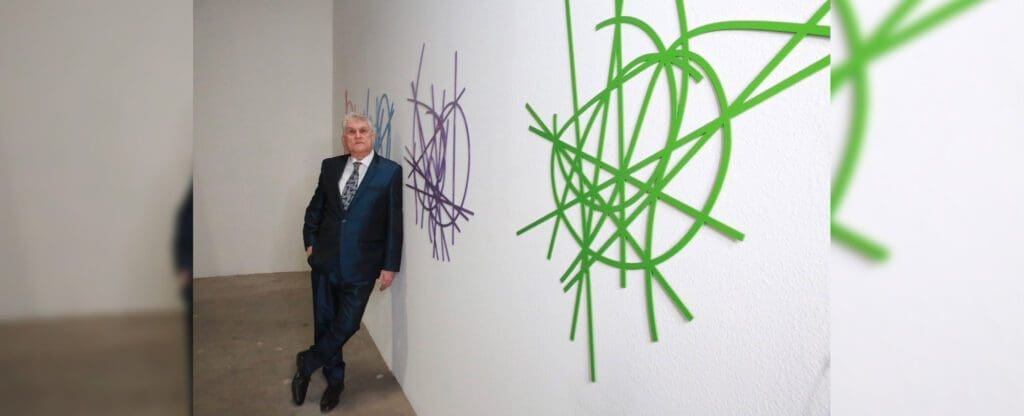 Man in suit leaning by green purple sculptures