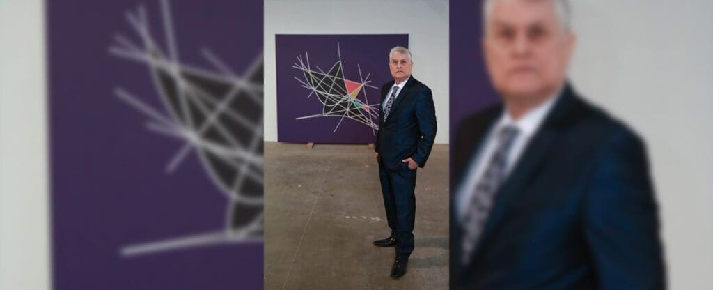Well-dressed man posing by geometric art piece
