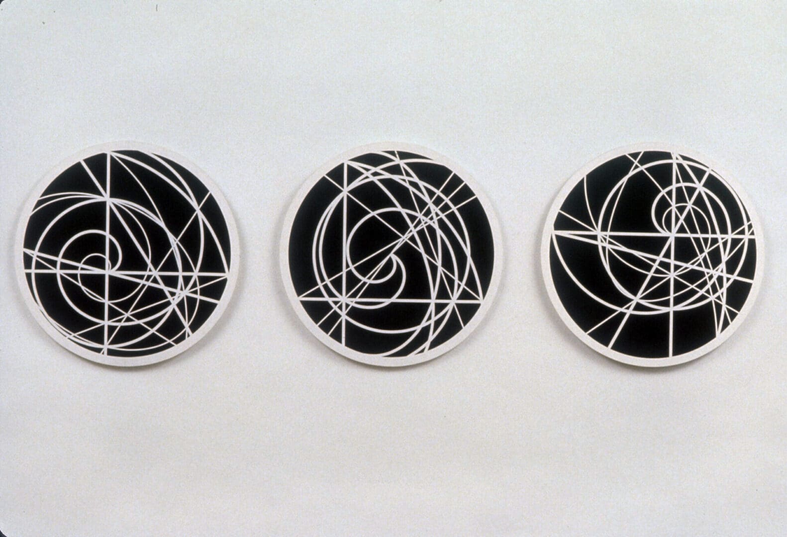 Three circular black and white paintings on a wall.