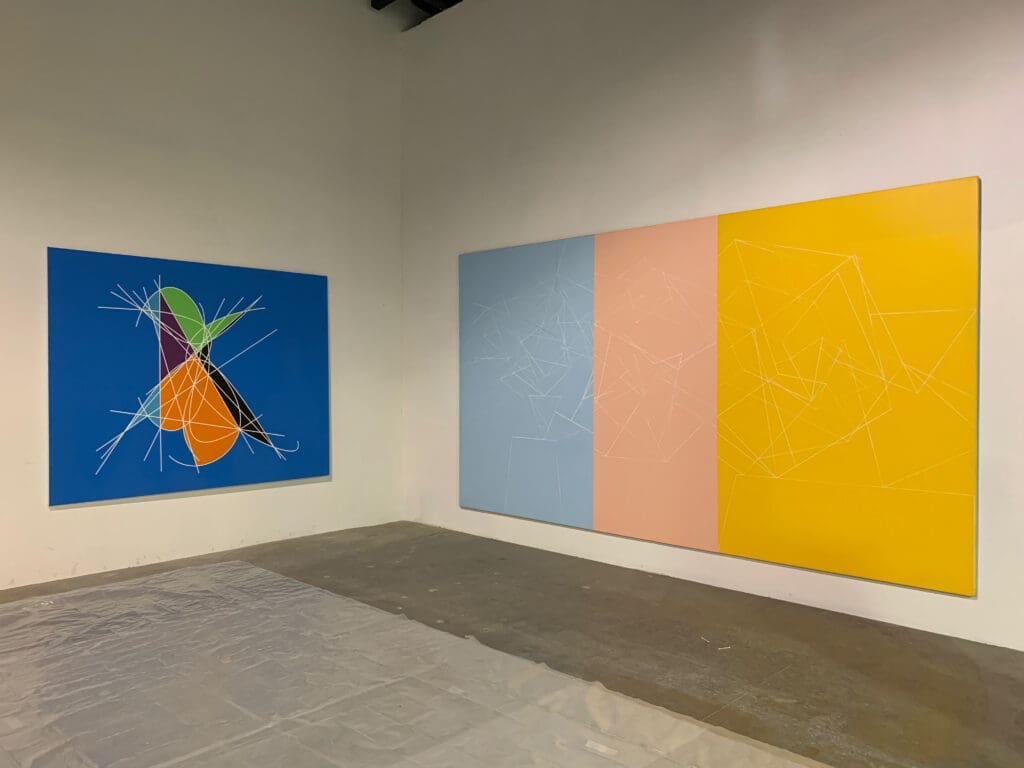 Abstract paintings with vibrant colors displayed in a modern gallery.