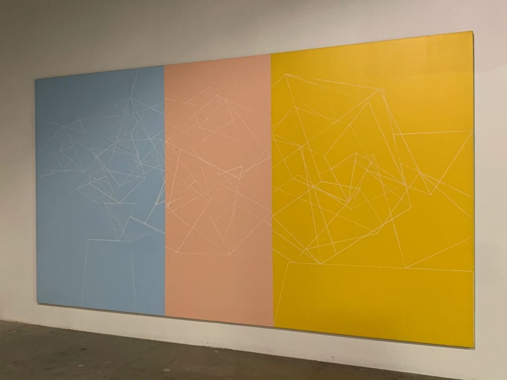 Three large rectangular panels in blue, peach, and yellow colors on a wall.
