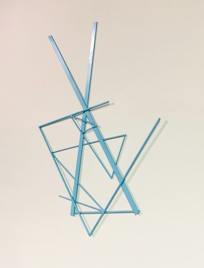 An abstract sculpture made of intersecting blue acrylic rods against a plain background.