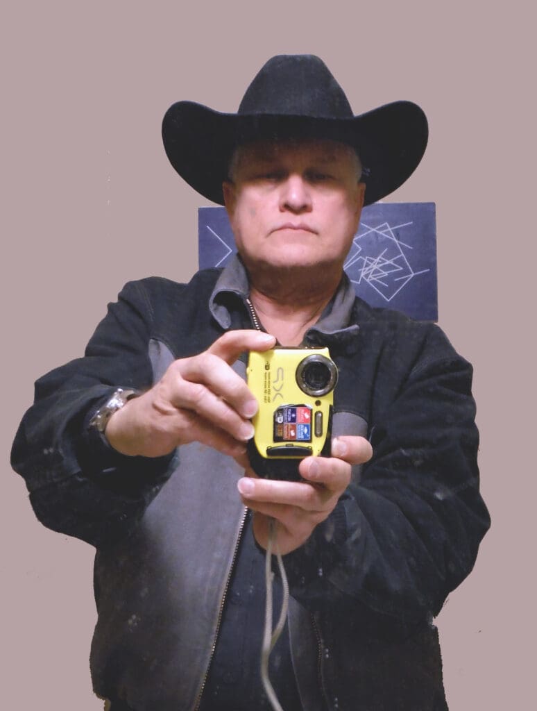 Person wearing a black cowboy hat taking a photo with a yellow camera.
