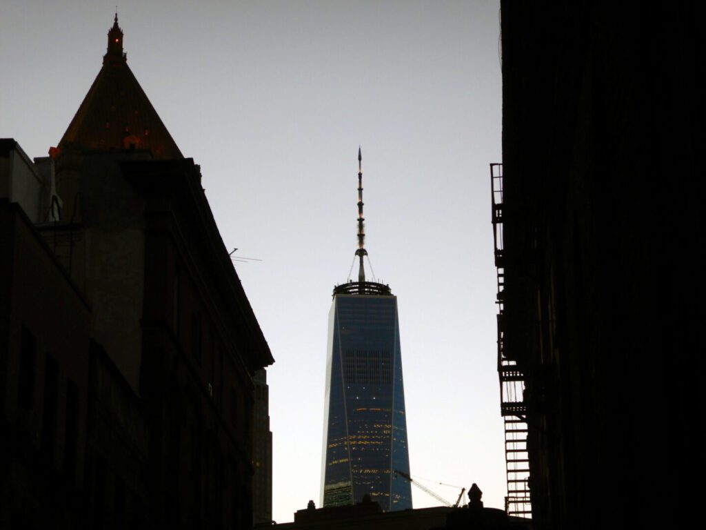 One World Trade Center silhouette between dark buildings