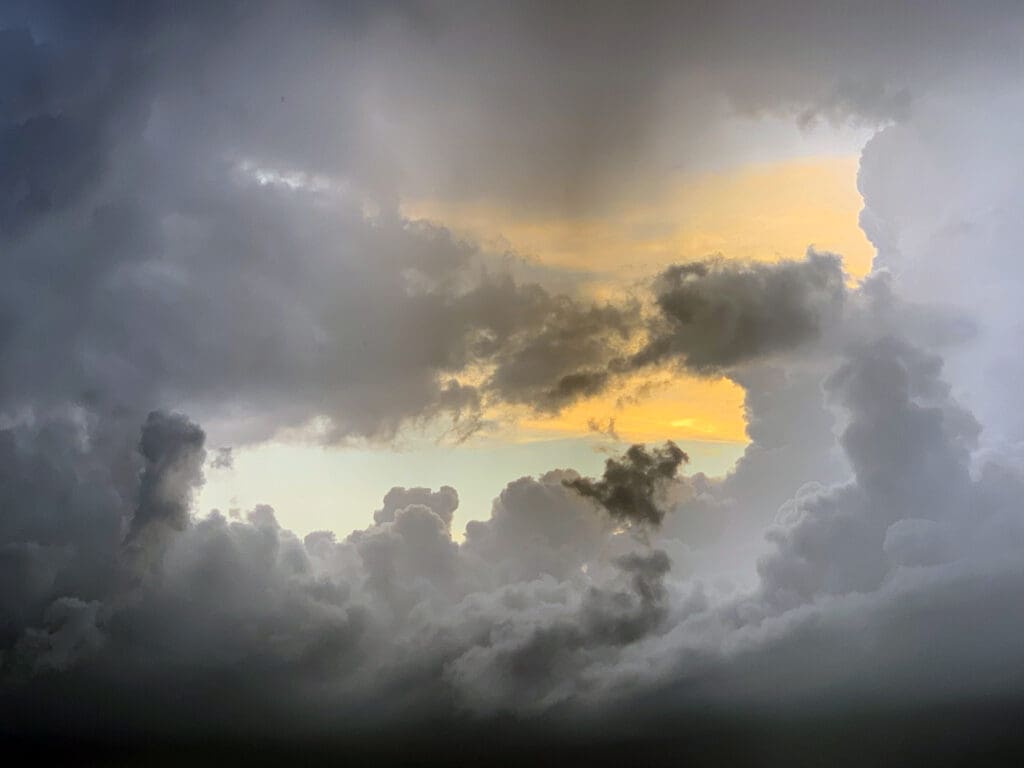 A dramatic sky with dark clouds framing a glowing orange sunset.