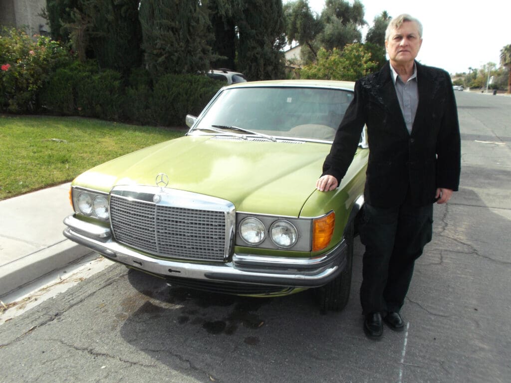 Man standing next to a vintage green Mercedes-Benz car.