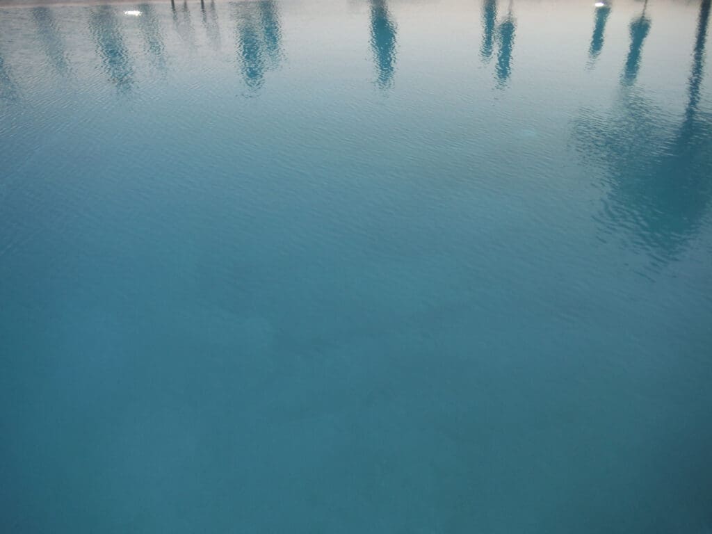 Blurry reflection of people on a calm water surface.