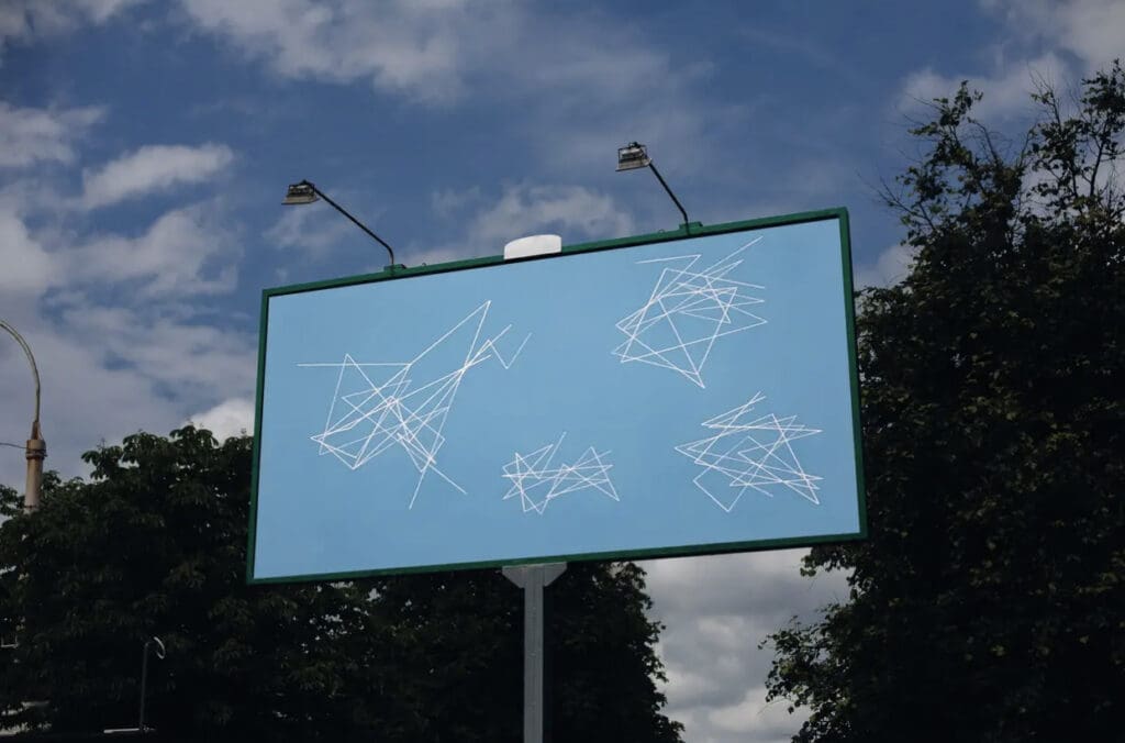 A sky-blue billboard with white abstract line drawings against a partly cloudy sky.