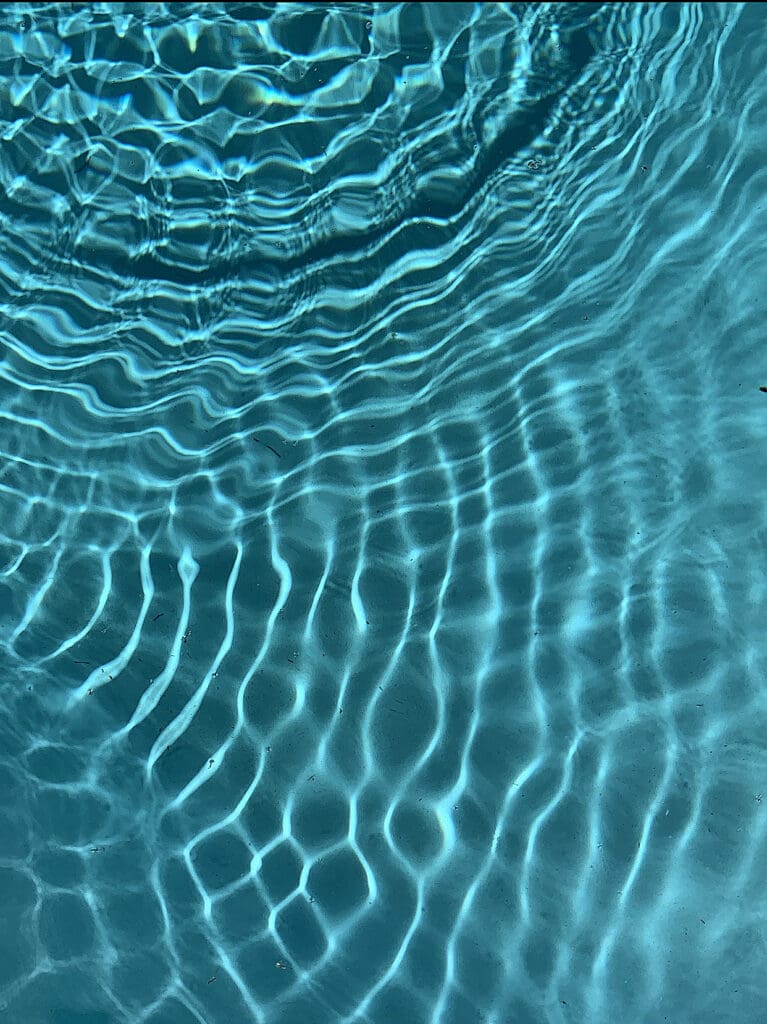 Sunlight creates rippling patterns on clear blue water.