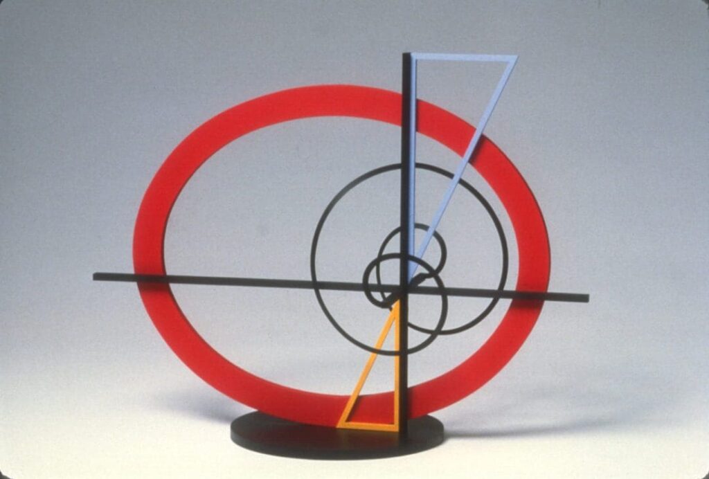 Abstract geometric sculpture with circles and triangles in red, black, gray, and yellow.