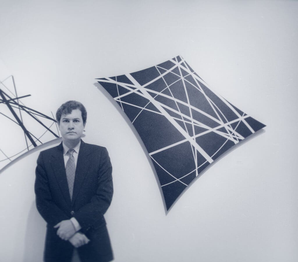 Man standing by abstract geometric artwork.