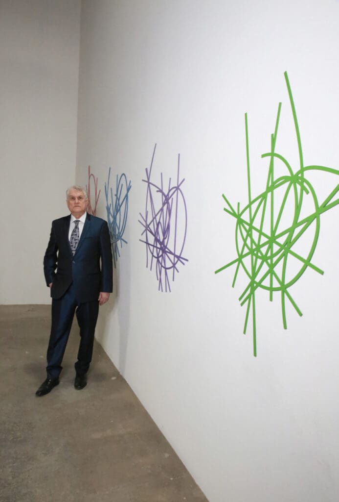 Man in suit beside green and purple murals