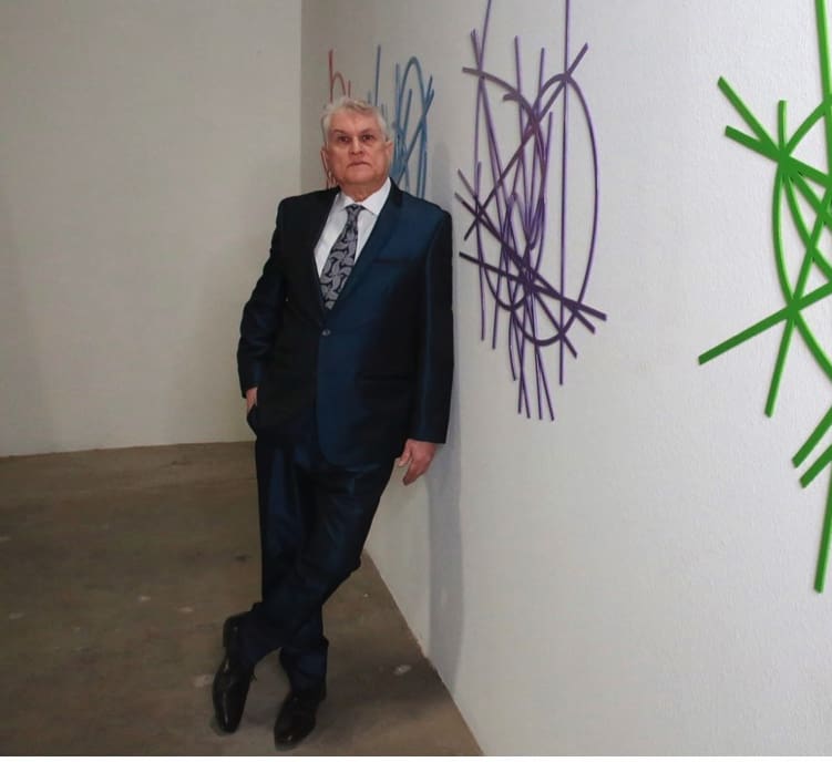 Man in suit leaning against graffiti wall.