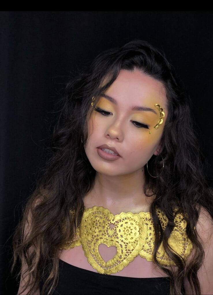 Woman with gold makeup and lace design.