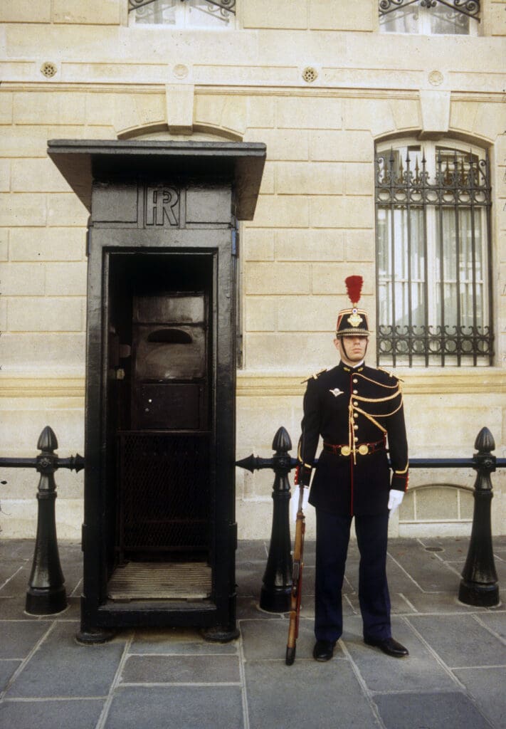 Guard standing beside a black sentry box.