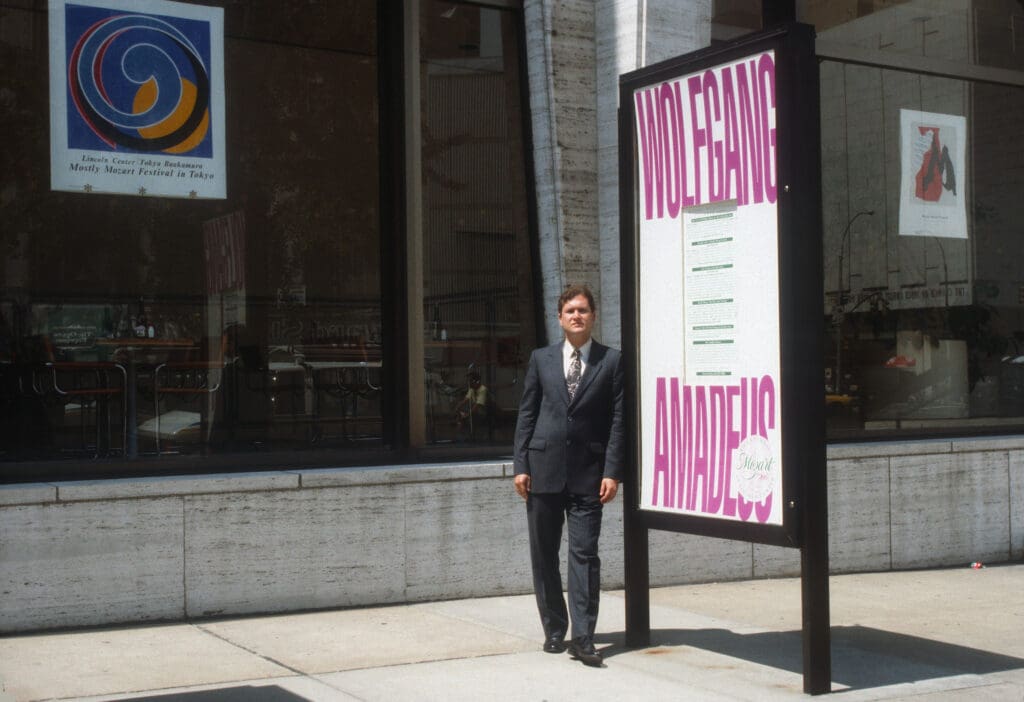 Man standing beside Wolfgang Amadeus sign.