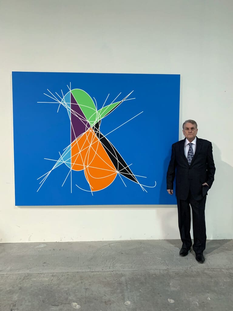 Man standing beside abstract colorful painting.