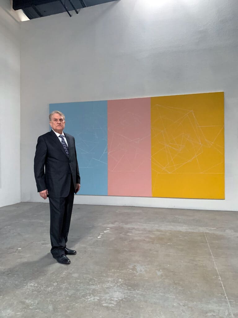 Man in suit before pastel triptych painting