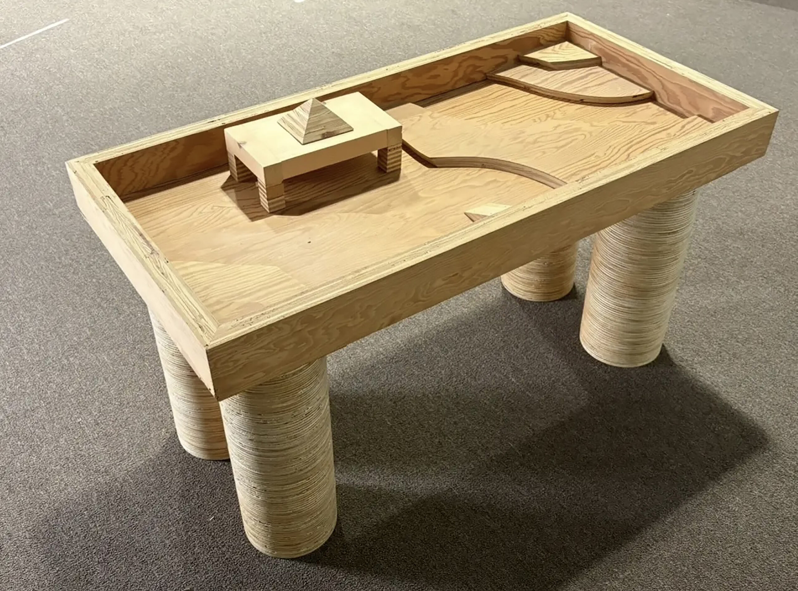 Handcrafted wooden table with cylindrical legs and a small raised section.