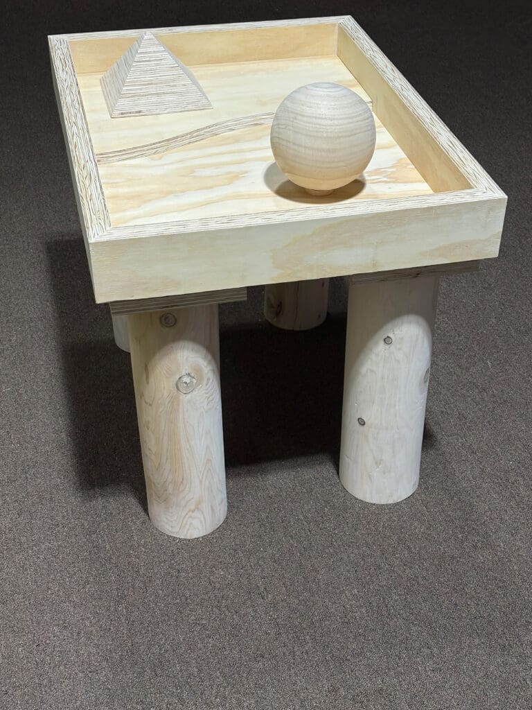 A wooden table with four cylindrical legs and a wooden sphere on top.