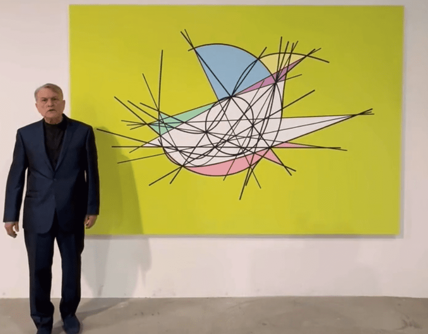 Man standing next to a large abstract painting with bright colors.