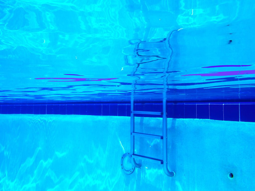 Blue-tinted underwater ladder and rippled reflections