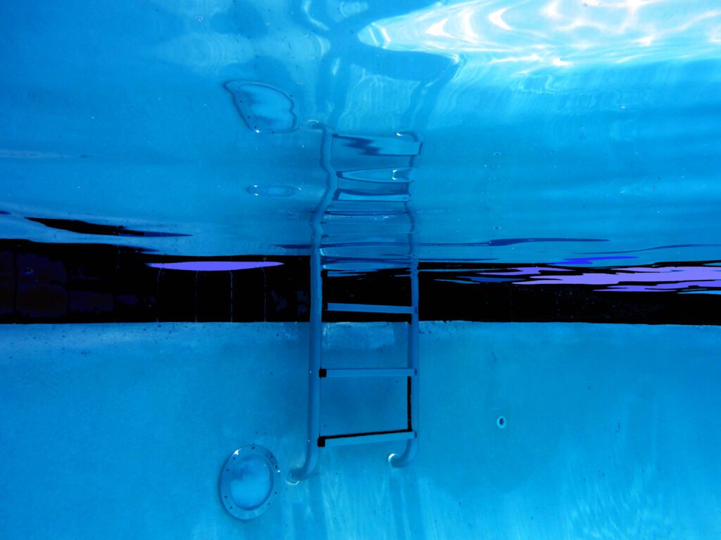 Submerged stainless ladder with shimmering water patterns