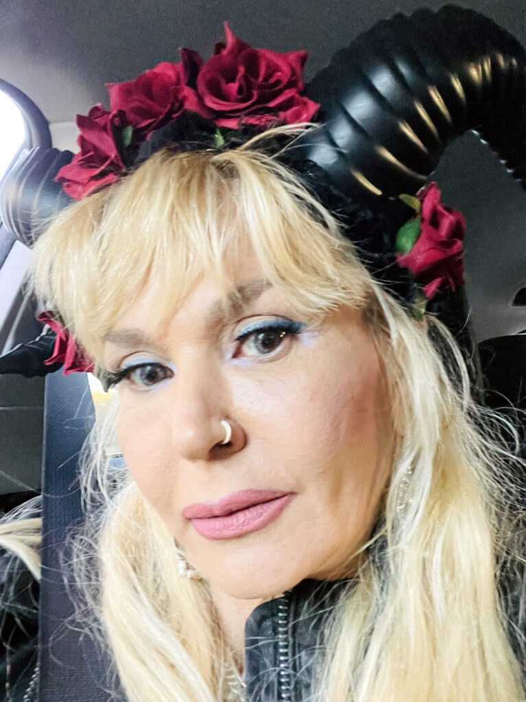 Blonde woman wearing horn headpiece with red roses