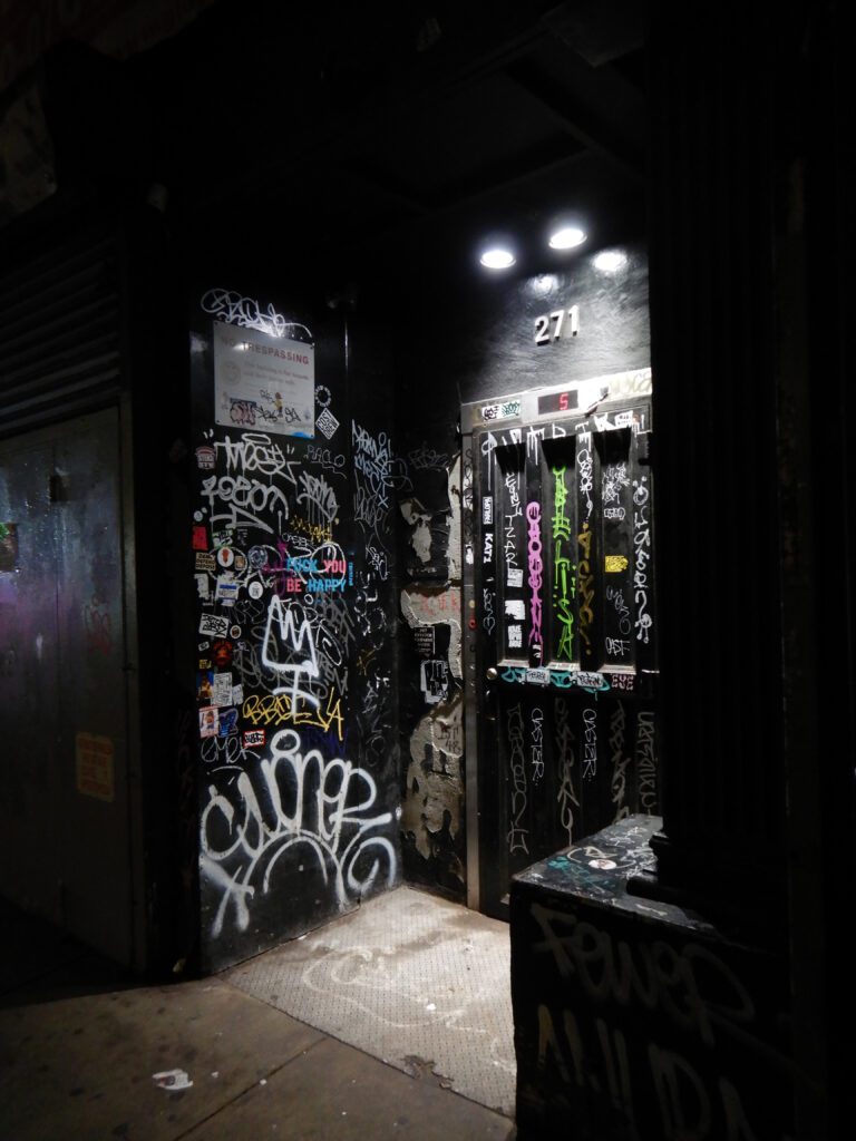 Narrow sticker-covered doorway under two lights