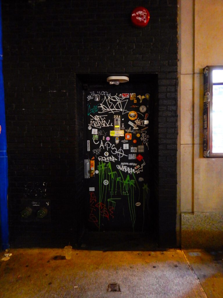 Graffiti-covered black service door with green paint drips