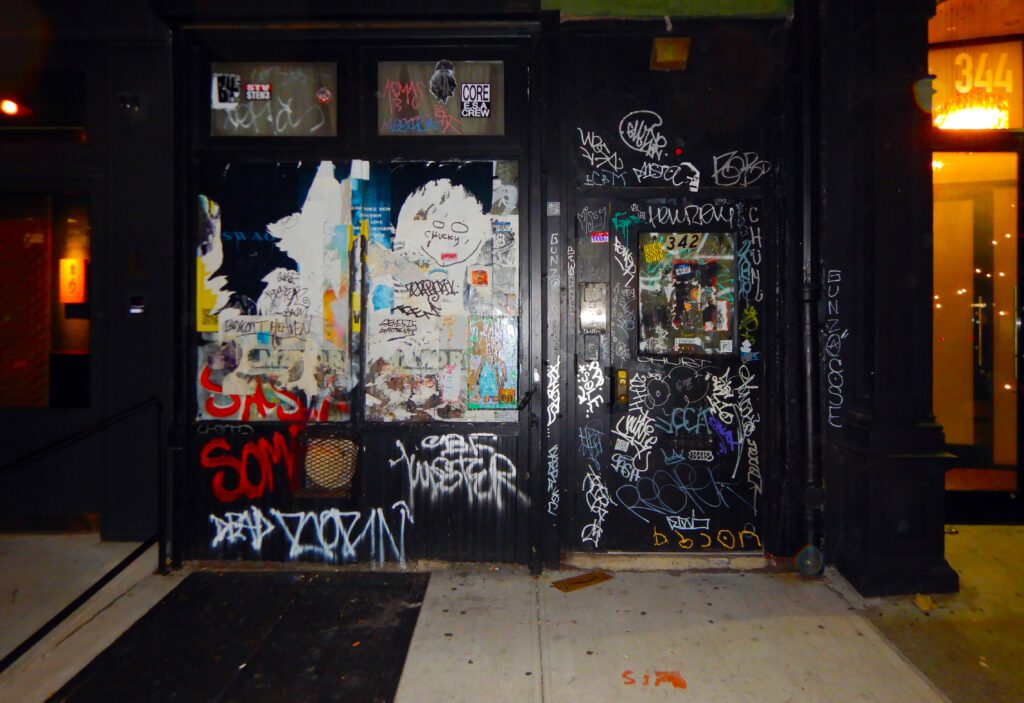 Lit doorway covered in stickers and graffiti
