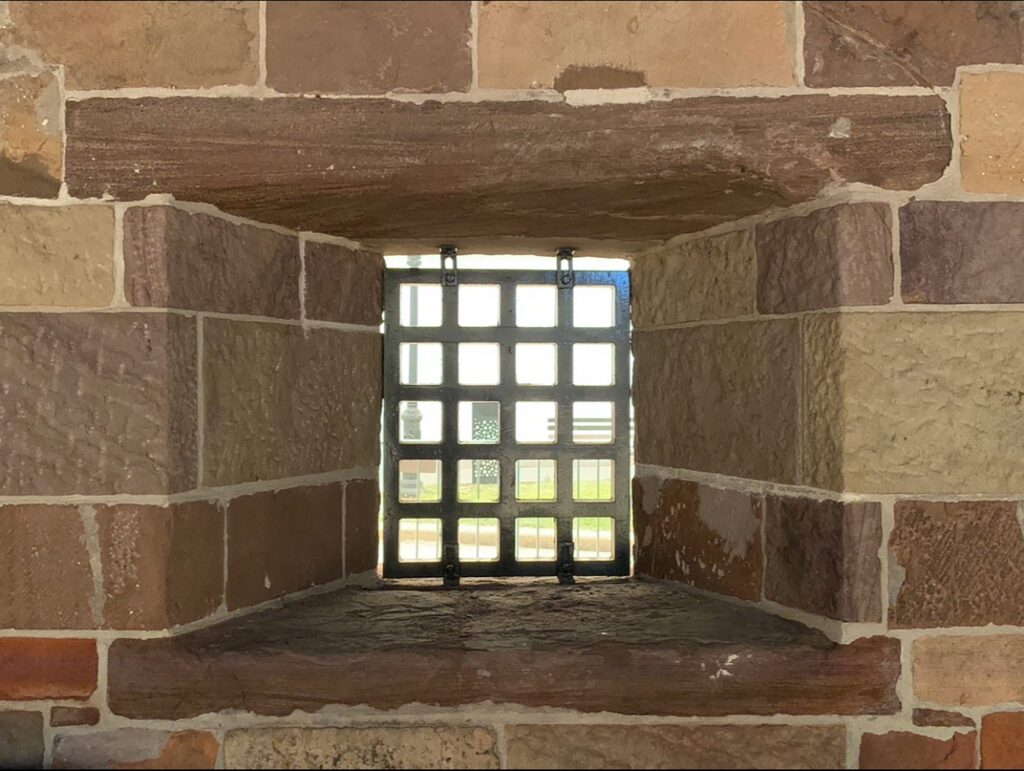Small barred window set in sandstone wall
