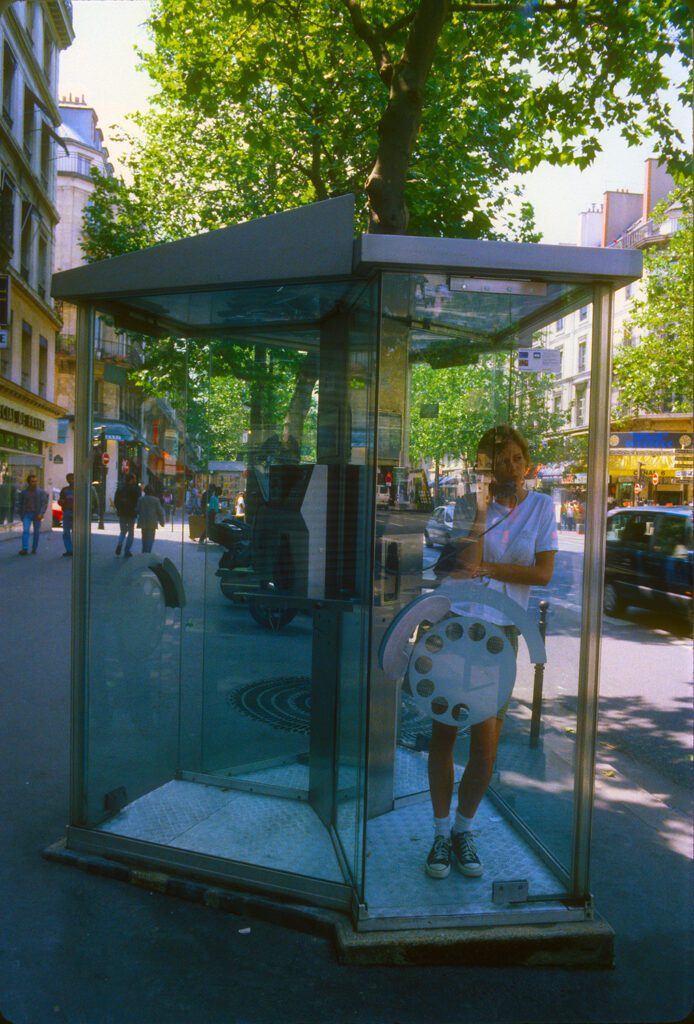 Woman in glass phone booth on sidewalk